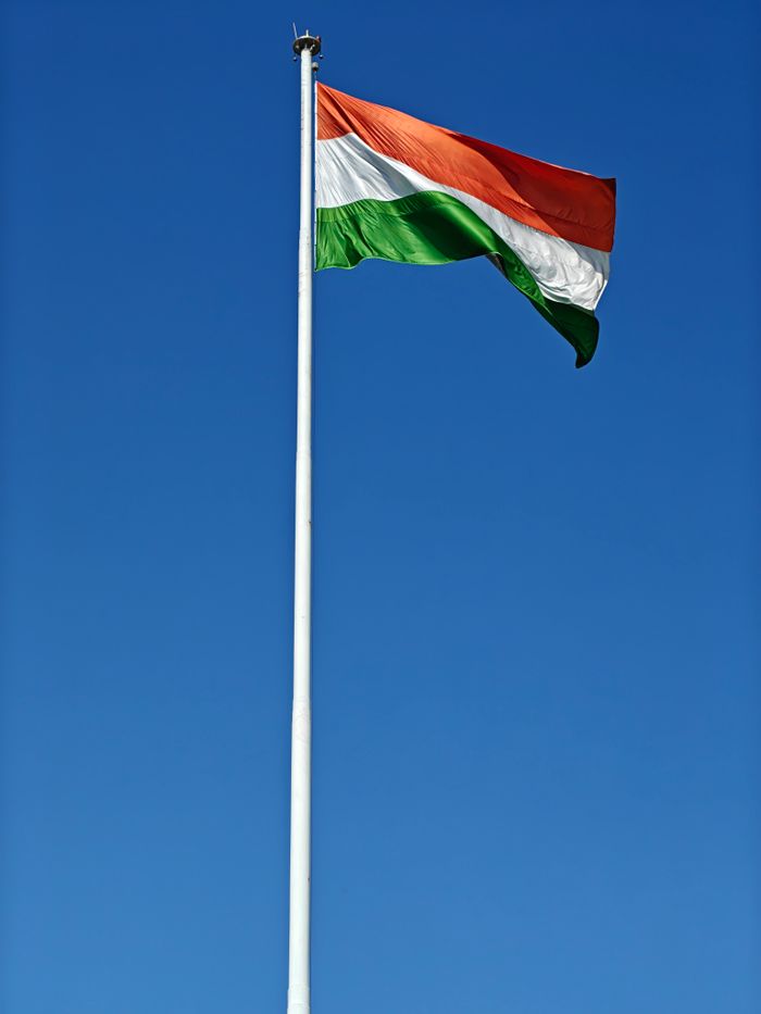 team-03 The Indian national flag waving in a clear blue sky, symbolizing patriotism.