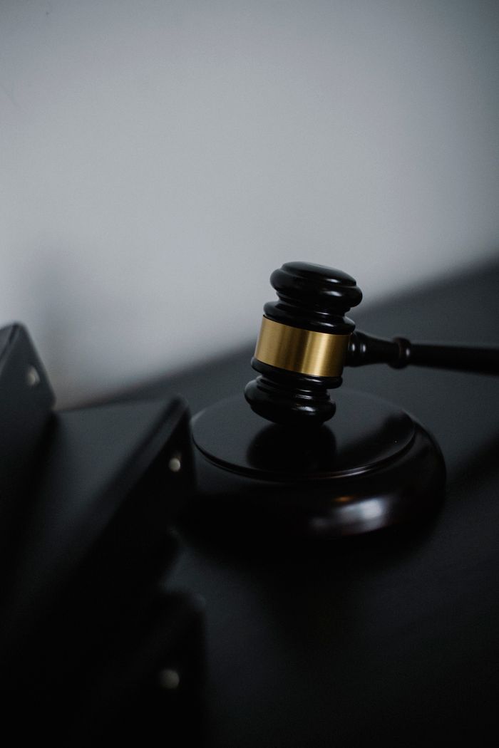 who-we-are Black wooden gavel with golden strip on table near stack of folders in courthouse