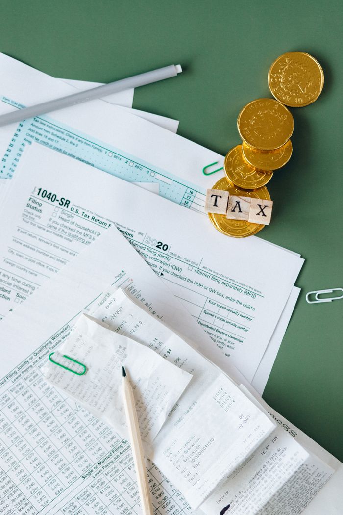 team-01 Tax documents and gold coins on a green desk symbolizing financial planning and savings.