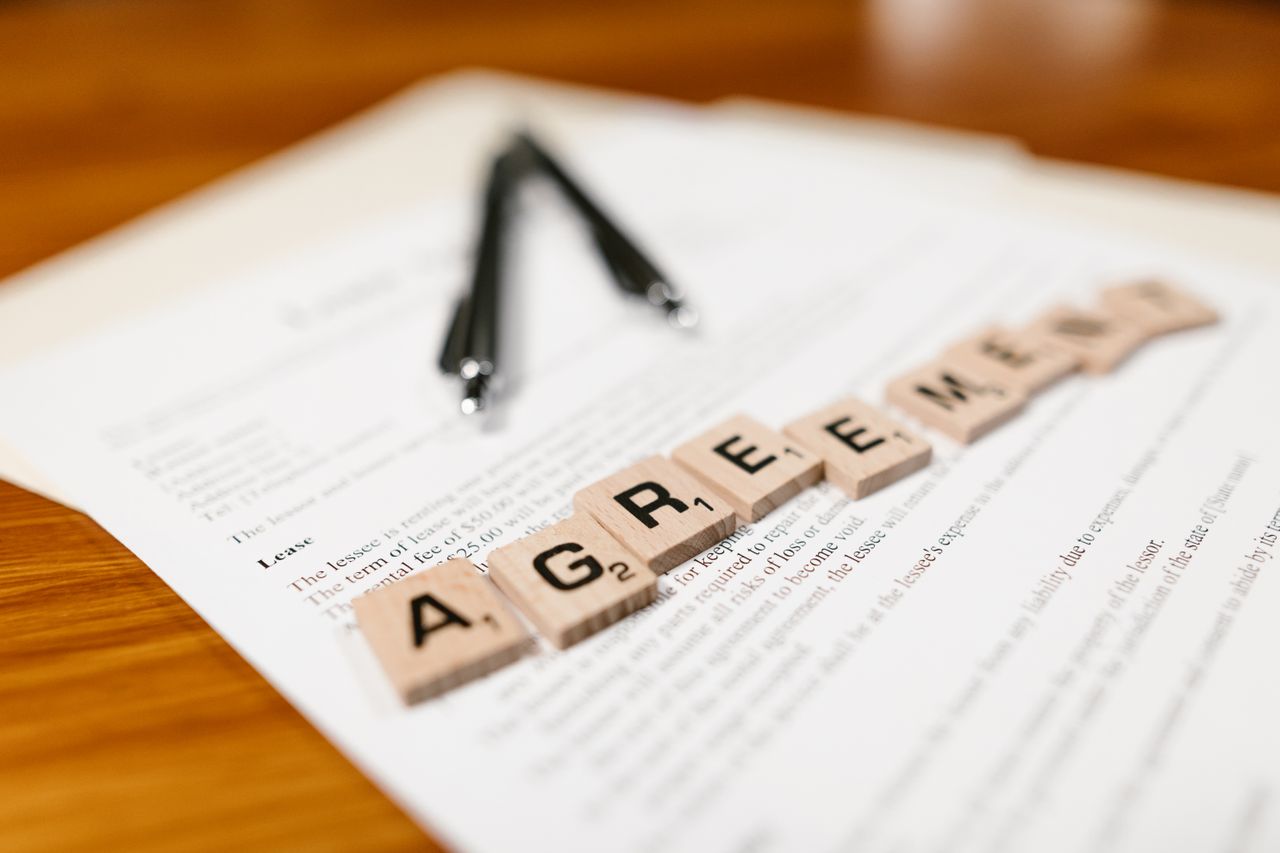 Mastering the First Impression: Your intriguing post title goes here Scrabble tiles spelling 'AGREEMENT' on a lease document, emphasizing contractual themes.