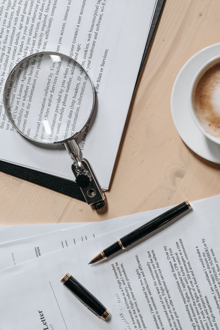 The Art of Drawing Readers In: Your attractive post title goes here Top view of documents with a magnifying glass and pen, ideal for business or legal themes.