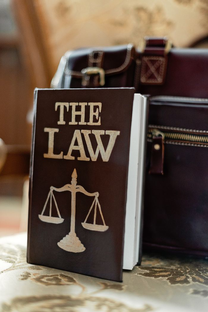 who-we-are Close-up of a law book titled 'The Law' beside a leather briefcase.